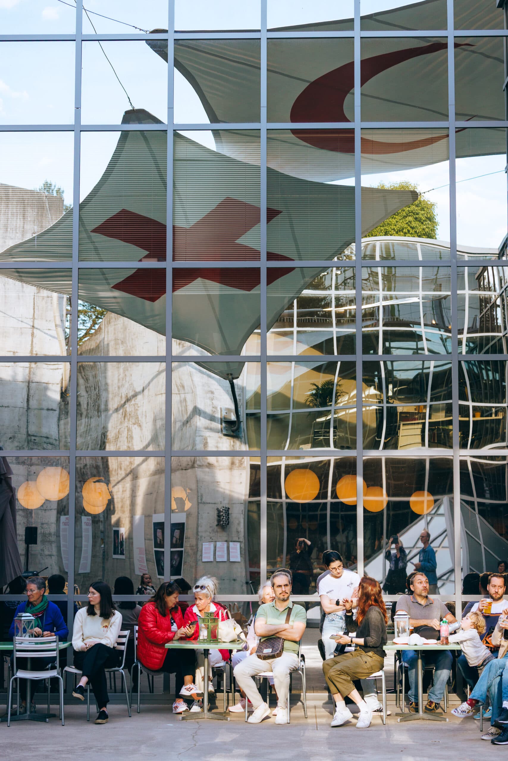 Large interior space filled with light, featuring a glass structure and the Red Cross and Red Crescent emblem flags, with visitors