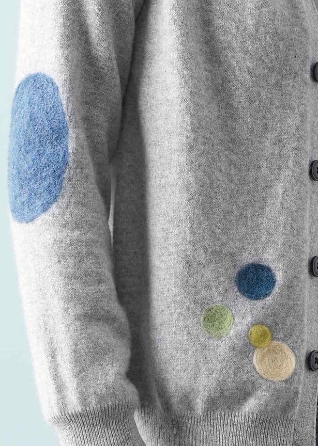 Ronds colorés en feutre sur une jaquette en laine grise